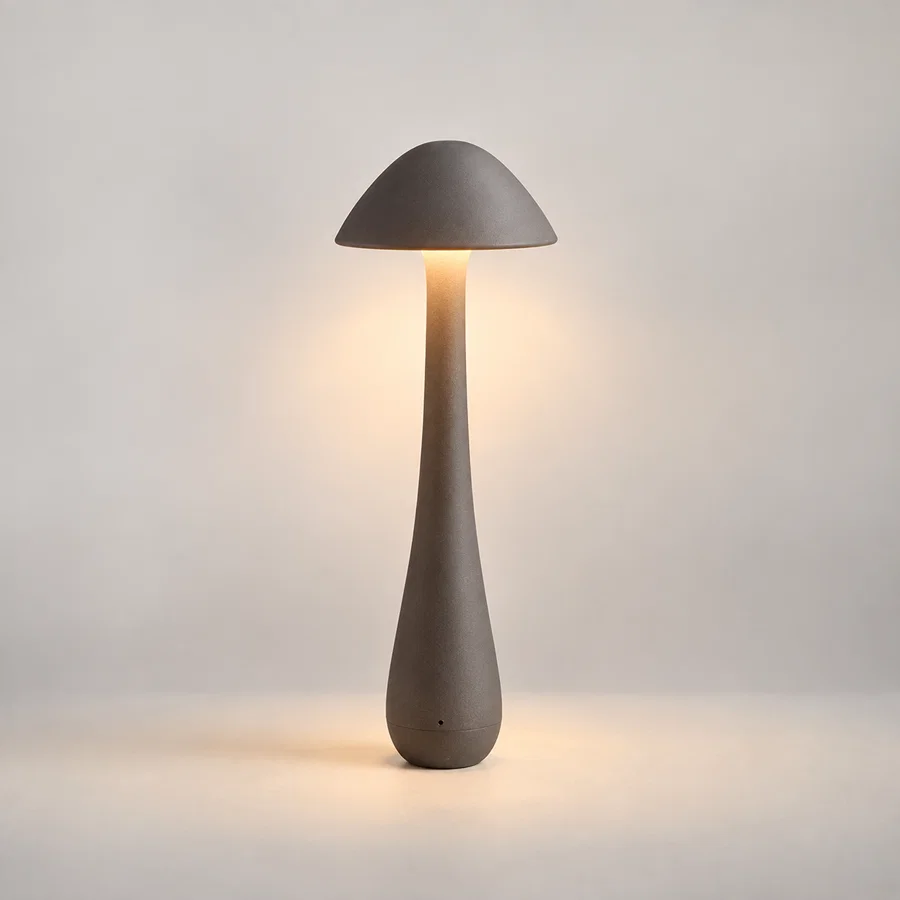 A mushroom-shaped table lamp with a matte gray concrete-like finish, shown lit against a soft neutral background.