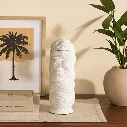 Tall white ceramic vase with sculptural textured detailing styled on a wooden console beside framed artwork and indoor plants for a cozy decor look.