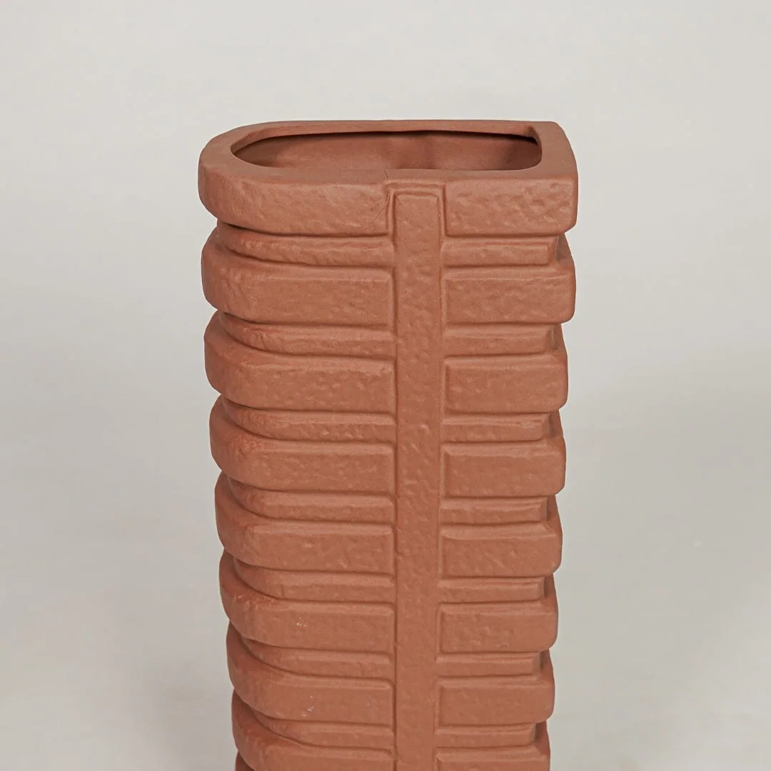 Closeup of terracotta ceramic vase with ribbed textured finish for elegant tabletop and shelf decor styling.
