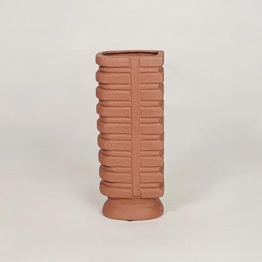 Terracotta ceramic decorative vase with geometric ribbed texture for modern tabletop and shelf decor placement.