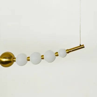 Close view of linear pendant light with frosted glass globes and gold metal rod highlighting premium modern lighting design.
