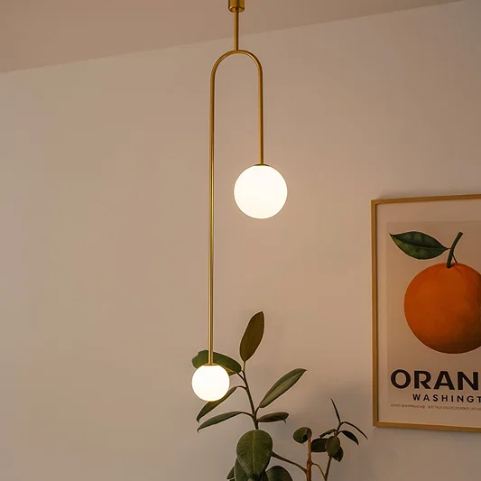 Gold metal pendant light with globe glass shade creating warm ambient lighting for modern living room interiors.