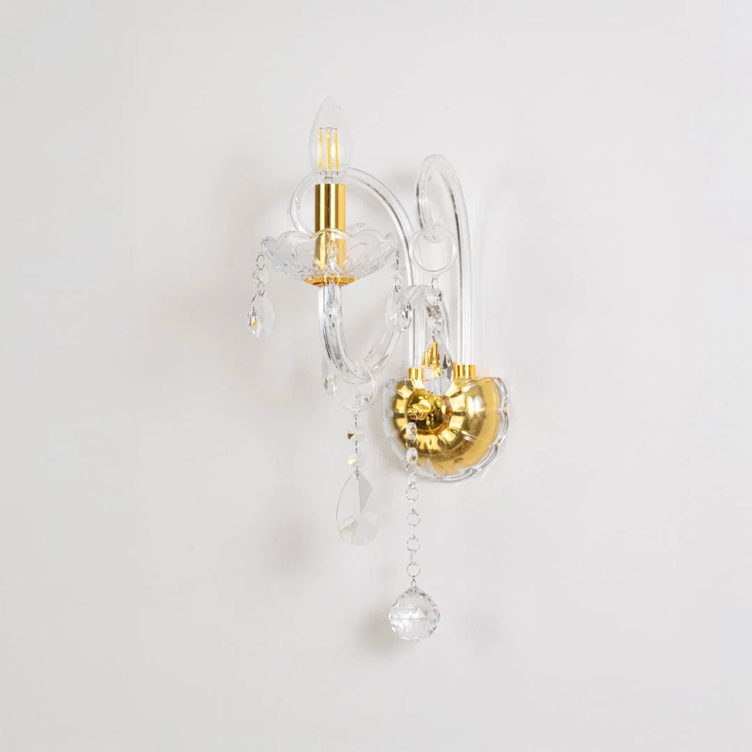 Crystal wall light with golden base and drops elegant wall mounted table lamping on off white background.