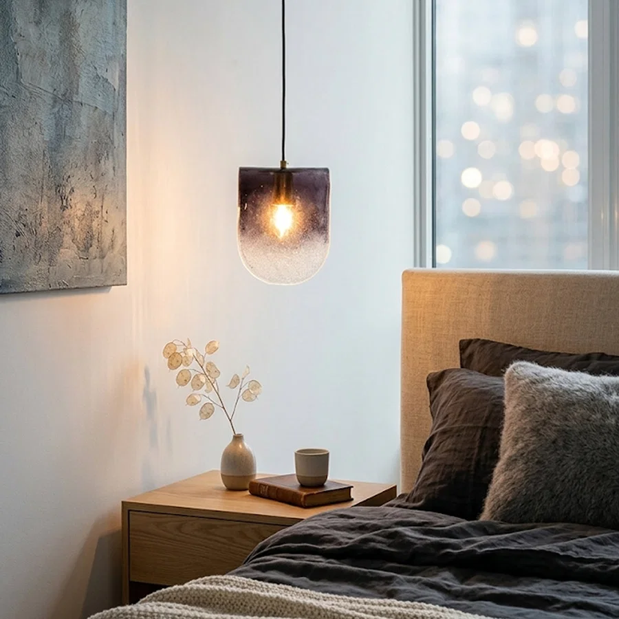 Frosted glass pendant light with warm glow installed beside bed against interior wall background creating cozy ambient bedroom lighting decor appeal.