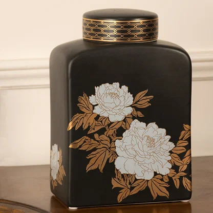 Black ceramic decorative jar with white floral artwork displayed on a console table for elegant modern home decor.