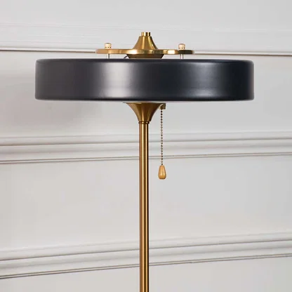 Closeup of modern black and gold table lamp showing round metal shade with sleek detailing and golden accents.