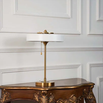 Minimal white table lamp with gold stand placed on a white background showing its smooth finish and modern silhouette.
