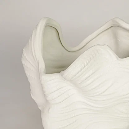 Closeup of white ceramic decorative vase with flowing wave texture showcasing premium craftsmanship and styling.