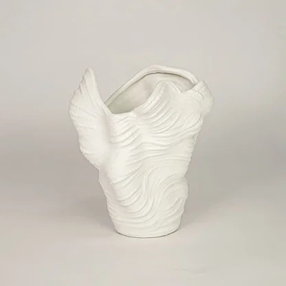 White ceramic decorative vase with flowing sculptural silhouette for modern shelf styling and home decor displays.