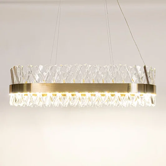 Gold metal chandelier with clear crystal rods shown with lights on against a white background highlighting its glowing sophisticated illumination.