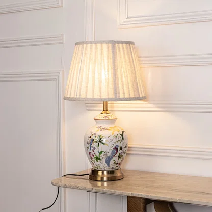 White floral ceramic table lamp with fabric shade styled on a side table creating timeless classic interior lighting.