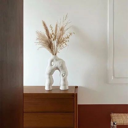 White ceramic abstract sculpture styled with pampas grass on a console table for modern home decor settings.