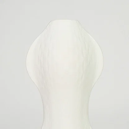 Closeup image of white ceramic abstract vase for modern shelf placement with textured matte artistic finish styling.
