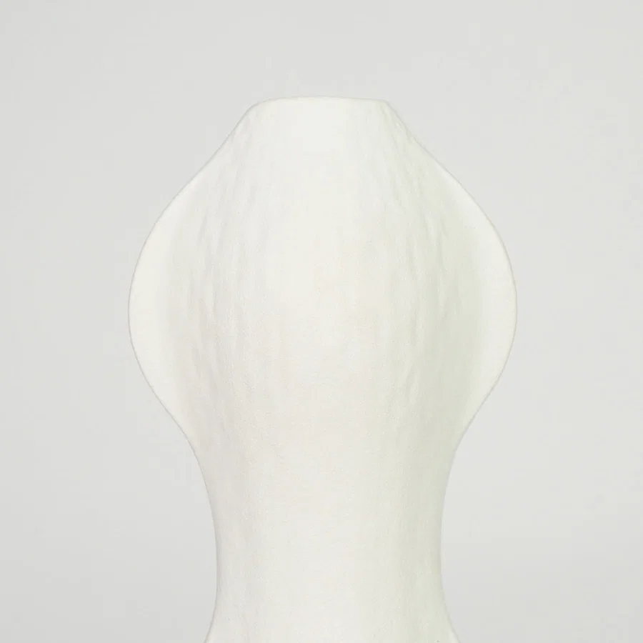 Closeup image of white ceramic abstract vase for modern shelf placement with textured matte artistic finish styling.