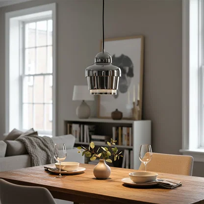 Silver metal pendant light suspended above dining table adding contemporary elegance to a modern living room setting.