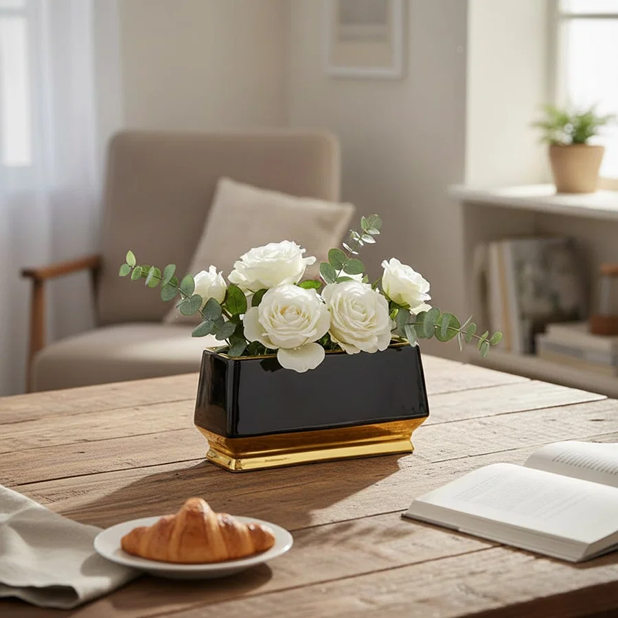 Black and gold metal planter styled on table in modern living room setting for elegant home decor display.