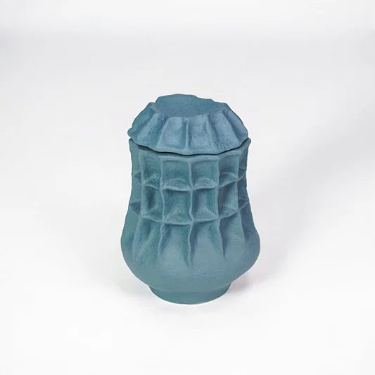 White background image of blue ceramic textured jar for modern tabletop decor styling with artistic matte finish.
