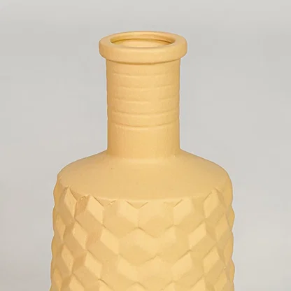 Closeup yellow ceramic geometric textured vase surface detail modern decorative flower vase for living room table shelf decor styling.
