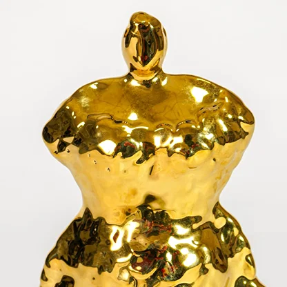 Close up view gold ceramic figurine showing sculpted female form glossy finish decorative sculpture accent for shelf styling home.
