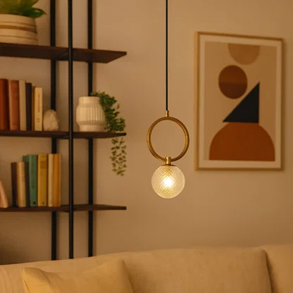 Gold metal wall light with frosted glass globe creating warm ambient lighting in a modern living room setting.