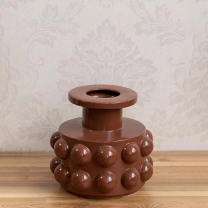 Brown ceramic decorative vase with bubble detailing styled on a wooden table for warm modern home decor displays.