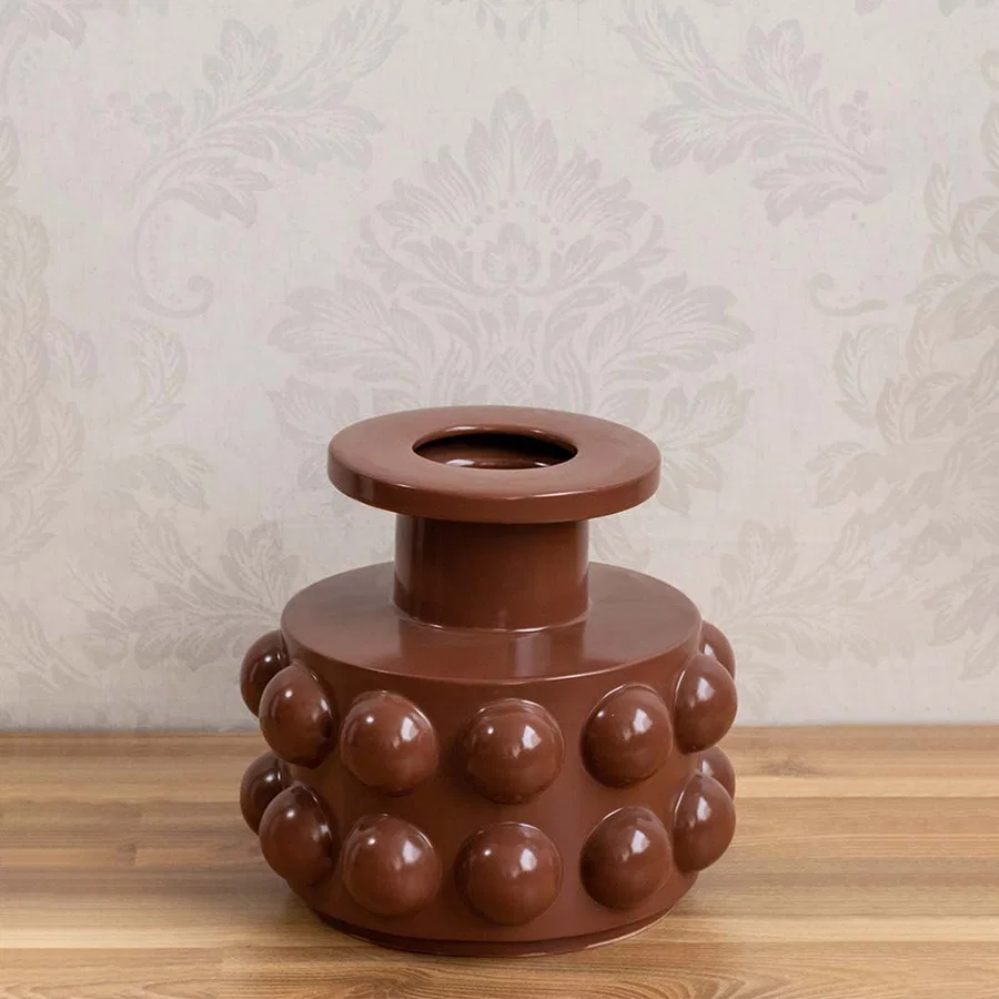 Brown ceramic decorative vase with bubble detailing styled on a wooden table for warm modern home decor displays.
