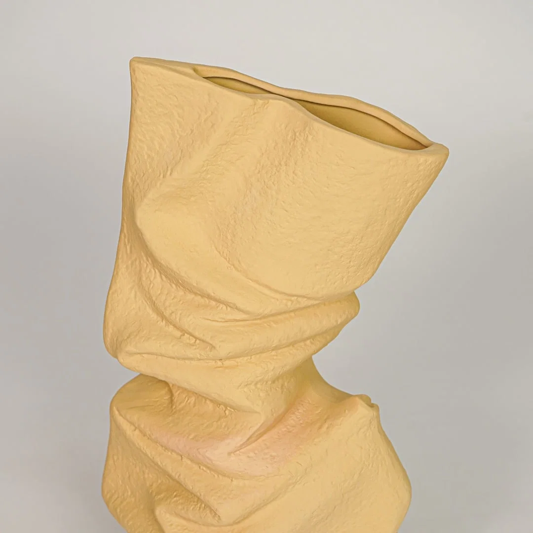 Closeup of beige ceramic vase with twisted sculpted texture for modern tabletop and shelf decor styling ideas.