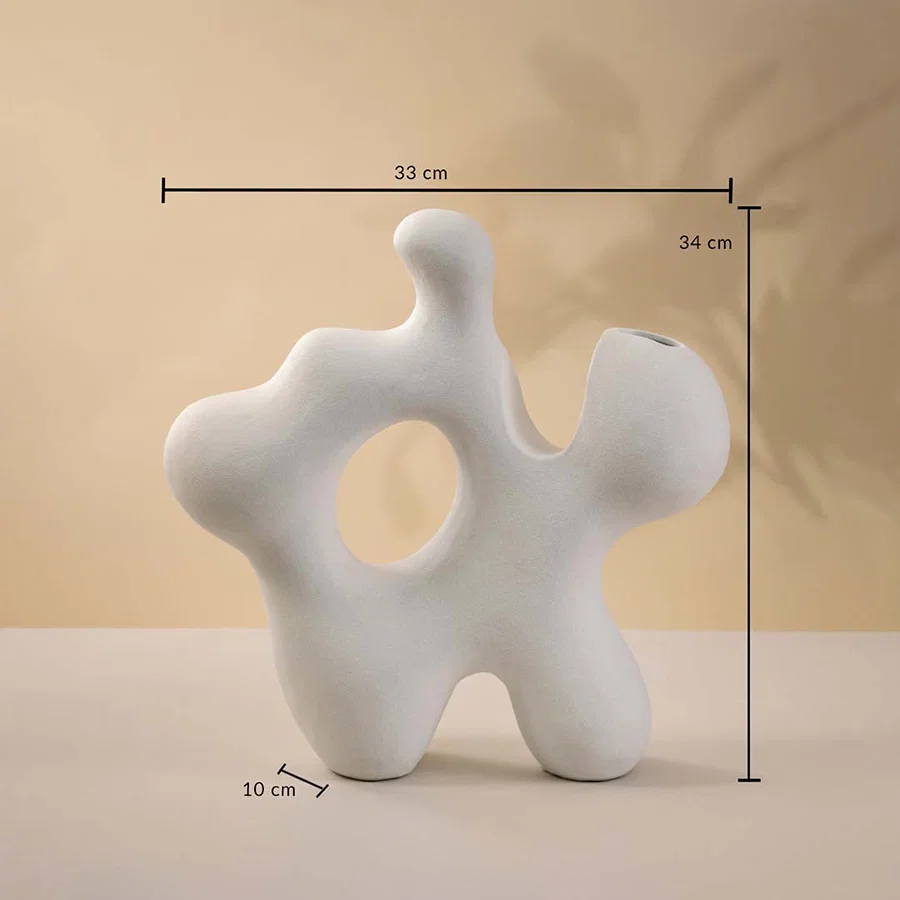 Dimension image of large abstract white ceramic sculpture vase with organic cutouts cast against shadows showing 34 cm height and 31 cm width.