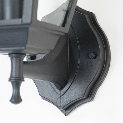 Closeup image of black metal outdoor wall light base with textured finish for durable exterior decor.