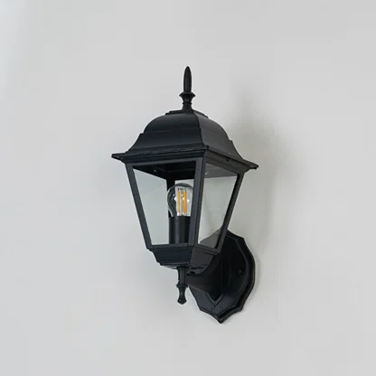 Classic black outdoor wall light shown off on white background highlighting refined lantern body and decorative finial.